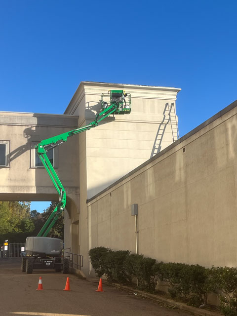 Crew painting commercial exterior from a lift